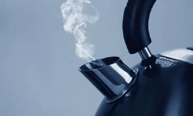 Red tea drink is boiled in a glass kettle on a gas stove, close-up